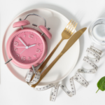 Composition symbolique autour d’une horloge et de couverts, illustrant la notion de chrono-nutrition ou de rythme alimentaire. Formation en ligne : Gain de minceur (perte de poids) en ligne ou en présentiel, Charente Maritime