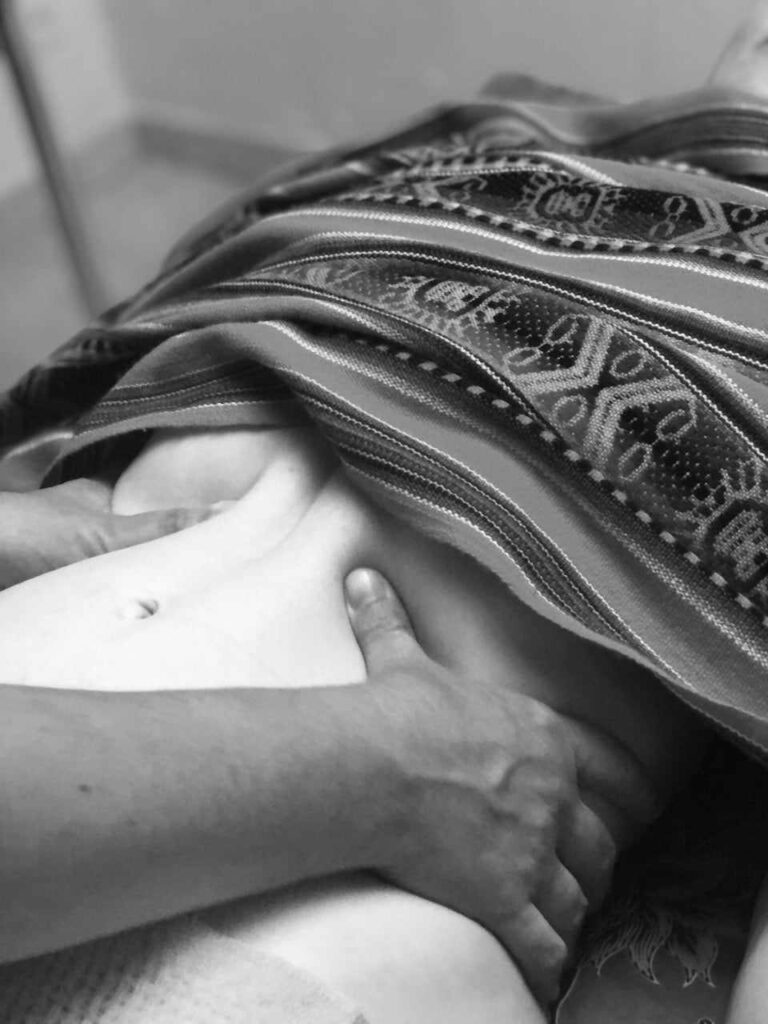 Geste manuel sur un ventre, une technique de massage ou soin abdominal (Chi Nei Tsang, drainage, etc.).