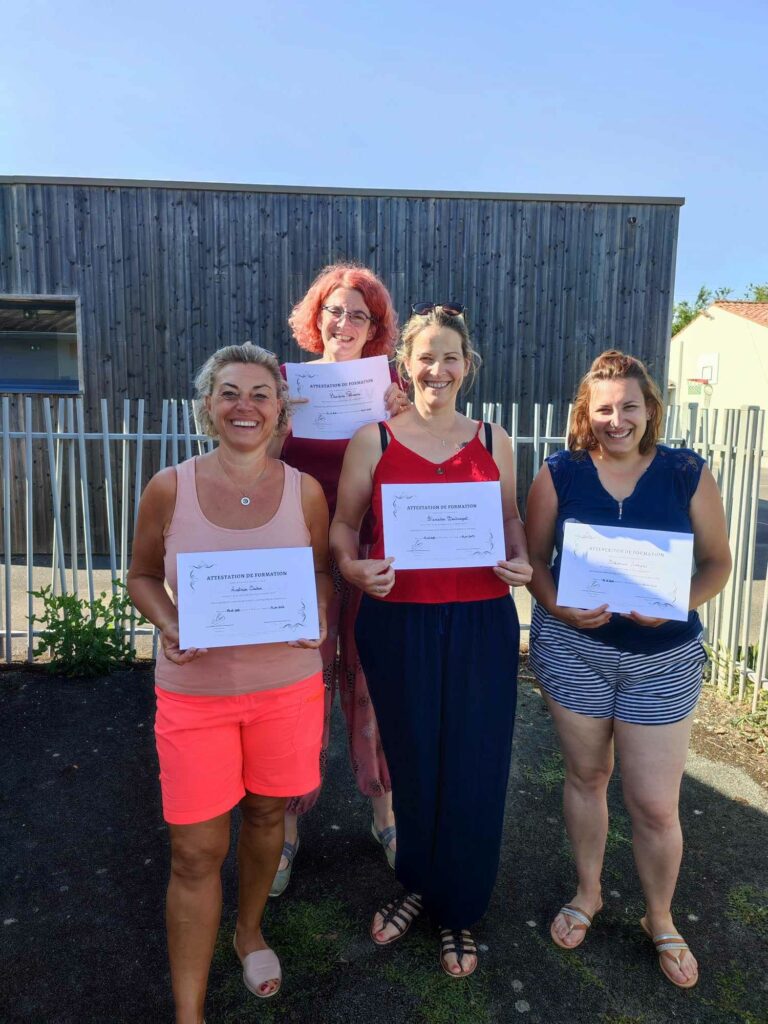 Autre groupe de stagiaires avec leurs certificats en extérieur, ambiance conviviale et fière.